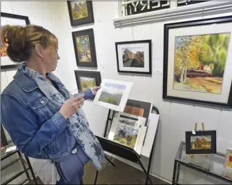  ?? Photos by Dan Watson/ The Signal ?? (Left) Local band “Kel’isa” entertains during the reception of the Keep It Local: 661 Art Show held at Santa Clarita Artists Associatio­n in Newhall on Saturday. (Above left) Attendee Sue Mangione examines some of the artwork on display during the event’s reception.