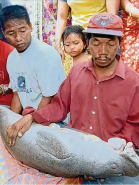  ?? — Filepic ?? Pak Atan (right) and his family members could not hold back their tears as they held the dead body of Si Tenang, the baby dugong, back in 1999.