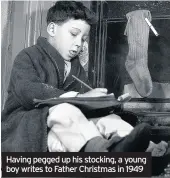  ??  ?? Having pegged up his stocking, a young boy writes to Father Christmas in 1949