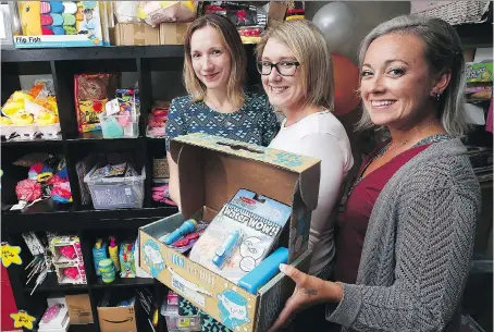  ?? DAN JANISSE ?? Lisa Homenick, left, Danielle Moldovan, centre, and Michelle Vandenbrin­k display their Fun-In-The-Box gift pack on Monday. The three mothers started the online business that ships boxes full of toys to kids.