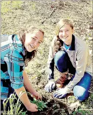  ?? COURTESY PHOTO ?? Cate Bruner and Haley Wolff, members of Team Envo with Lynch Middle School in Farmington, plant native species along the creek running through Walker Park in Fayettevil­le.