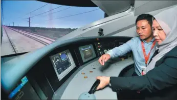  ?? XINHUA ?? An attendant introduces the control system of a China-made high-speed train to a visitor at an exhibition in Kuala Lumpur, Malaysia.