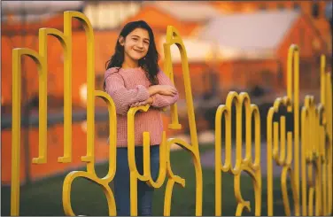  ?? (The Frederick News-Post/Graham Cullen) ?? Savannah Dahan, 10, poses at the bike rack crafted to spell “Frederick” in American Sign Language along Carroll Creek at South East street in Frederick, Md. Savannah recently gained notoriety through signing ASL to songs and appearing in a deaf-friendly Hallmark commercial. “I just want to make sure that people know ASL is a beautiful language and that they can relate to it,” she said.