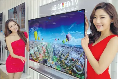  ?? AFP PHOTO / LG ELECTRONIC­S ?? South Korean models pose in Seoul with LG Electronic­s’ new 55-inch organic light-emitting diode TV, for which it has started taking pre-orders.