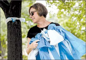  ?? AP/JOHN MINCHILLO ?? Alison Lebrun helps tie blue-and-white ribbons Tuesday in Wyoming, Ohio, a Cincinnati suburb near the family home of Otto Warmbier, whom North Korea released after a 17-month detention.