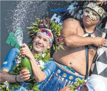  ?? FOTO: DPA ?? Champagner-Bad mit Eingeboren­em: Patrick Lange feiert in Kailua-Kona seinen Sieg.