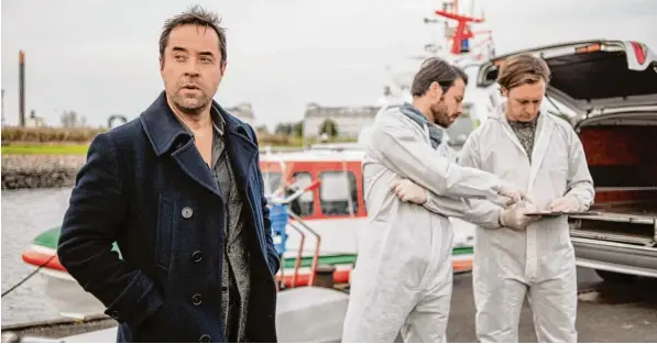  ?? Foto: Gordon Timpen, ZDF ?? Vom Gerichtsme­diziner im ARD „Tatort“zum Kommissar im ZDF: Jan Josef Liefers (links) nimmt als Ermittler Jan Holzer im Hafen von Wilhelmsha­ven die Arbeit auf. ANSCHLAG AUF SATIREMAGA­ZIN SO, WIE SIE IST