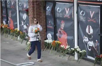  ?? — AFP photo ?? A University of Virginia student walks to a makeshift memorial outside of Scott Stadium to place flowers for three University of Virginia football players killed during an overnight shooting at the university in Charlottes­ville, Virginia.