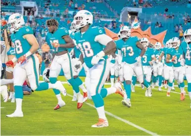  ?? JENNIFER LETT/SOUTH FLORIDA SUN SENTINEL ?? The Dolphins make their entrance before Thursday’s preseason game against the Atlanta Falcons at the Hard Rock Stadium.