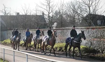  ?? — AFP photos ?? Jockey Page Fuller (second right) rides horse at Jamie Snowden’s stables in Lambourn, Berkshire, west of London.