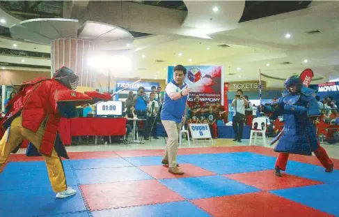  ??  ?? Sen. Migz Zubiri, an arnis champion and president of PEKAF, referees a match during the federation’s National Battle of Champions (above). Action on the mat at a qualifying tournament in LapuLapu City, Cebu (top).