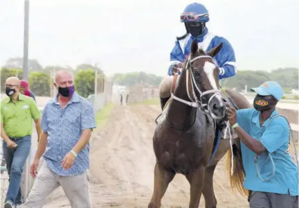  ?? (Photo: Naphtali Junior) ?? Another Affair bounces into the winners’ enclosure with jockey Dane Dawkins in the saddle. At left (in blue shirt) is trainer Gary Subratie.