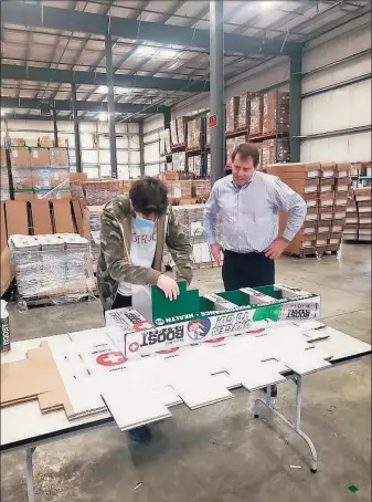  ?? Contribute­d photo ?? Noah Engel of the Southport section of Fairfield, left, puts together a display for Boost Oxygen, as the company’s founder and CEO, Rob Neuner, admires his work.