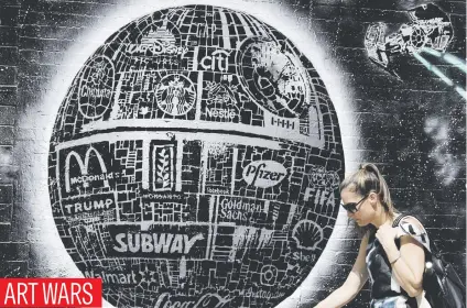  ?? Picture: EPA ?? A woman walks past a film series mural featuring the corporate Death Star and Tie-Fighters by Australian street artist ‘CRISP’ on the Lower East Side of New York City on Monday.