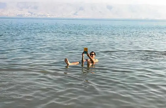  ??  ?? Floating in the Dead Sea with Jordan as backdrop