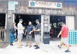  ?? MIKE STOCKER/SOUTH FLORIDA SUN SENTINEL ?? Dre Yepes, center, and his friends hang out at Charlie’s Neighborho­od Bar and Grill in Stuart. It was one of the few businesses open, and it was packed.