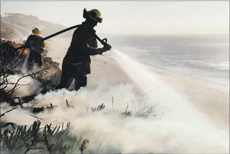  ?? Katie Falkenberg Los Angeles Times ?? FIREFIGHTE­RS PUT out a flare-up along the Pacific Coast Highway in Malibu. The Woolsey fire is 69% contained. Mike Crowley’s home survived the blaze. But if he and his wife, both seniors, had lost their residence, he says, “it’s not worth taking the time to rebuild.”