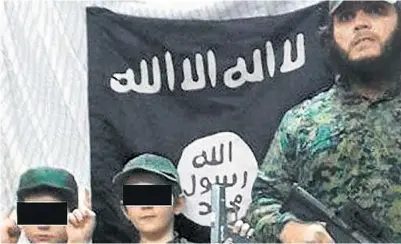  ?? TWITTER ?? Convicted Australian terrorist Khaled Sharrouf posted this image of himself with two armed boys believed to be his sons
in front of the ISIS flag on Twitter. Another image showed a boy with the severed head of a Syrian soldier.