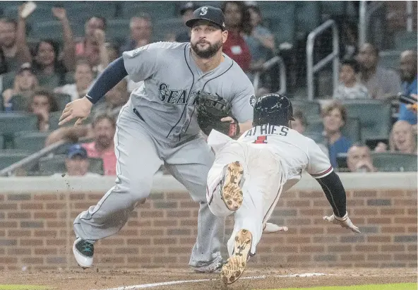  ?? AP ?? The Braves’ Ozzie Albies dives into home plate to score as Mariners first baseman Yonder Alonso waits for the throw Tuesday in Atlanta.