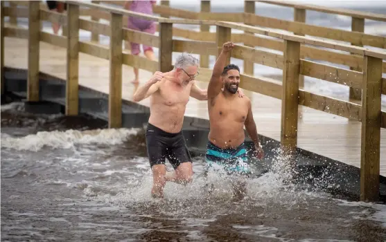  ?? Bild: Jari Välitalo ?? Per Brolléus och Daniel Sanjay hade all rätt att känna sig nöjda efter sitt dopp i havet. Vädergudar­na bjöd på isande vindar och tre graders ”värme” i vattnet under lördagens invigning av badbryggan i Skummeslöv­sstrand.