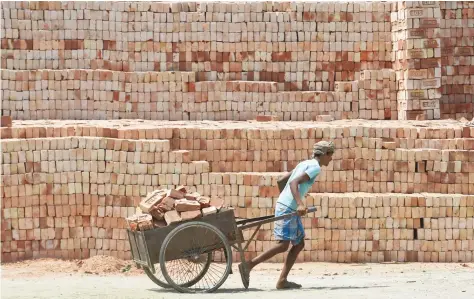  ?? — AFP ?? An Indian labourer moves bricks through a brick factory on the outskirts of Kolkata on Sunday. With the demand for bricks increasing to meet the growing infrastruc­ture and housing needs of a rapidly urbanising economy, the pace of shift to modern and...