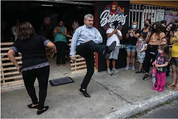  ?? Associated Press ?? ■ Fabio Rodolfo Vasquez, center, and his wife, Maria Moreno, dance at a promotiona­l event Sept. 19 outside a coffee shop, on the outskirts of Guatemala City. The couple entered an online dance contest during the new coronaviru­s pandemic to help them cope with the recent death of their daughter — and won it.