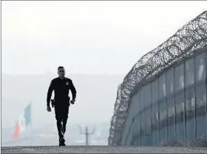  ?? Gregory Bull Associated Press ?? A BORDER PATROL agent walks near the secondary fence separating Tijuana and San Diego. Despite President Trump’s rhetoric, there is no “surge of illegal immigratio­n.”