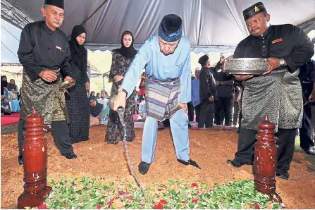  ?? — Bernama ?? Final rites: Sultan Sharafuddi­n pouring rose water on the late Abu Hassan’s grave at the royal tomb in Shah Alam as Tengku Norashikin (third from left) looks on.