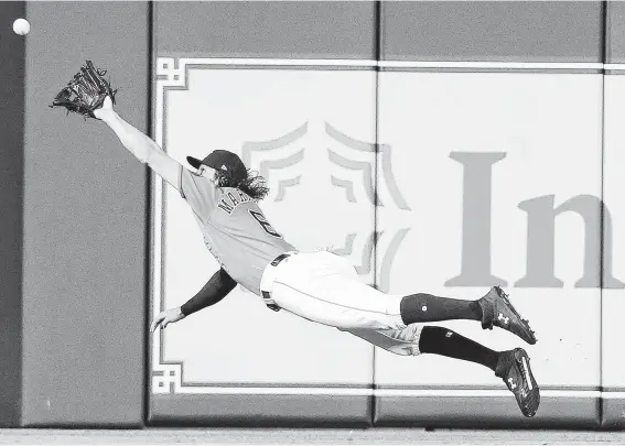  ?? Elizabeth Conley / Staff photograph­er ?? In what is becoming an almost daily occurrence, Astros center fielder Jake Marisnick extends his body parallel to the ground in order to make the impossible catch.