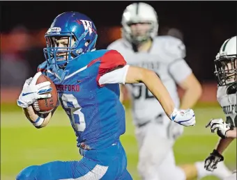  ?? SEAN D. ELLIOT/THE DAY ?? Waterford’s Sam Menders races away from Guilford defenders in Friday night’s high school football game at Waterford’s Alumni Field. Guilford won 28-14.