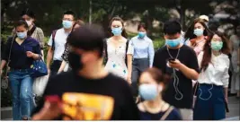  ?? PTI ?? Commuters wear face masks to protect against the new Coronaviru­s as they walk through the central business district in Beijing, Tuesday