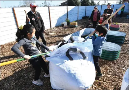  ?? PHOTOS BY CHRIS RILEY/TIMES-HERALD ?? Ella Goltiao, 8, and her brother Lio work to put shovels of dirt in planters Thursday at the new learning gardens at Faith Food Fridays in Vallejo.