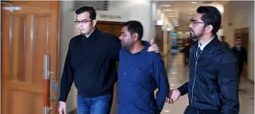 ??  ?? Rayhan (centre) escorted by MACC personnel to Sessions Court with two counts of giving bribes. — Bernama photo