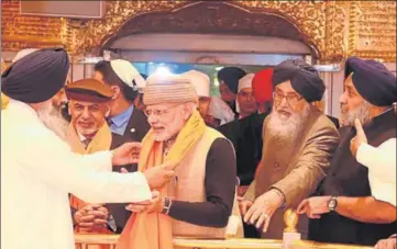  ?? GURPREET SINGH/HT ?? Prime Minister Narendra Modi being presented a ‘siropa’ at the Golden Temple as Punjab chief minister Parkash Singh Badal and deputy CM Sukhbir Badal look on; and (below) delegates paying homage to martyrs at Jallianwal­a Bagh in Amritsar on Saturday.