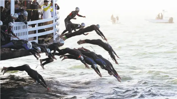  ?? Photos by Cody Glenn / Special to The Chronicle ?? Elite competitor­s dive off the San Francisco Belle to begin the Escape From Alcatraz Triathlon, which includes a bike ride and beach run.