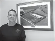  ?? Mona Weatherly ?? Above, Tim Chancellor of Broken Bow, the wean/finish supervisor for Thomas Livestock, LLC, stands next to a framed photo of the Buffalo barn, the first pork producing barn he owned.