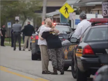  ?? TOM DODGE — THE COLUMBUS DISPATCH VIA AP ?? People hug as emergency personnel arrive to the scene of a shooting outside Pine Kirk nursing home in Kirkersvil­le, Ohio on Friday.