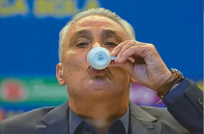  ?? CARL DE SOUZA / AFP ?? Técnico Tite teve tempo até para tomar um café durante a entrevista coletiva; Seleção fará dois amistosos