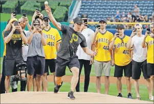  ??  ?? Pittsburgh Penguins captain Sidney Crosby throws out a ceremonial first pitch, as his teammates record the occasion, before a baseball game between the Pittsburgh Pirates and the Colorado Rockies on Tuesday.