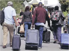  ??  ?? A family from Haiti is seen approachin­g an RCMP tent in Saint-Bernard-de-Lacolle, Que., as they haul luggage from Champlain, New York, in August 2017. Quebecers living by the Canada-U.S. border where thousands of migrants have been crossing into the country since 2017 will be eligible for up to $25,000 from the federal government.