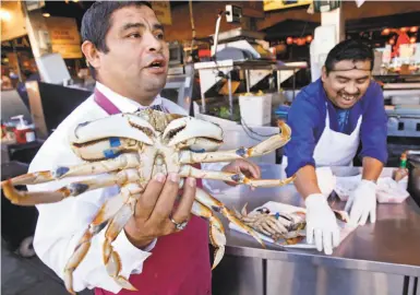  ?? Photos by Paul Chinn / The Chronicle ?? Jorge Cham ( left) and Jose Hoil peddle Dungeness crab imported from Washington state to tourists walking past Nick’s Lighthouse on Fisherman’s Wharf. The only local crab for sale is frozen from last season.