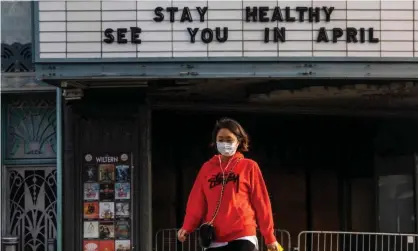  ??  ?? A woman walks past a closed venue in Los Angeles. Photograph: Apu Gomes/AFP/Getty