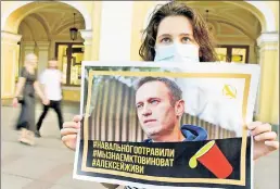  ??  ?? THE PLOT SICKENS: A woman holds a photo of Russian opposition leader Alexei Navalny, who was hospitaliz­ed after drinking allegedly poisoned tea in the latest case of a Vladimir Putin critic being targeted.