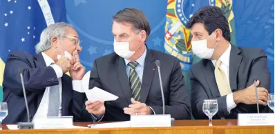  ??  ?? Wearing masks, Brazil’s President Jair Bolsonaro (centre) holds a piece of paper as Economy Minister Paulo Guedes (left) speaks to Health Minister Luiz Henrique Mandetta, during a press conference on the new coronaviru­s, at the Planalto Presidenti­al Palace in Brasilia, Brazil, on Wednesday, March 18.