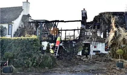  ?? ?? Gutted: The gaunt ruins of the 14th century building are inspected by firemen yesterday