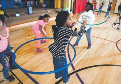  ?? Photos by Helen H. Richardson, The Denver Post ?? Priscilla Affloh, 8, foreground, and her classmates hula-hoop during Chris Strater’s physical education class at Lyn Knoll Elementary School in Aurora on Wednesday. A new report says physical education in Colorado is seriously lagging, but Strater is...
