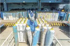  ?? — AFP ?? Workers for an oxygen supplies company prepare cylinders for distributi­on in Semarang, Central Java on Tuesday amid a surging demand for oxygen.