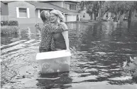  ?? DEDE SMITH / THE FLORIDA TIMES-UNION VIA AP ?? Florida residents wade through the streets of Jacksonvil­le, top and above, while boats are strewn around a Key Largo canal, right.