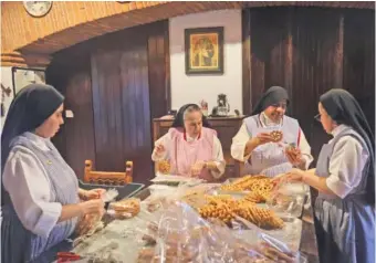  ?? AP PHOTO/GINNETTE RIQUELME ?? From left, nuns Alejandra Jaime, 39; Maria Ines Maldonado, 76; Maria Auxiliador­a Estrada, 59; and Patricia Marin, 28, store fritters with Christmas figures in plastic bags for sale Dec. 7 at the Convent of the Mothers Perpetual Adorers of the Blessed Sacrament in Mexico City.