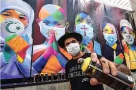  ??  ?? Brazilian mural artist Eduardo Kobra poses next to his recent work “Coexistenc­e”.